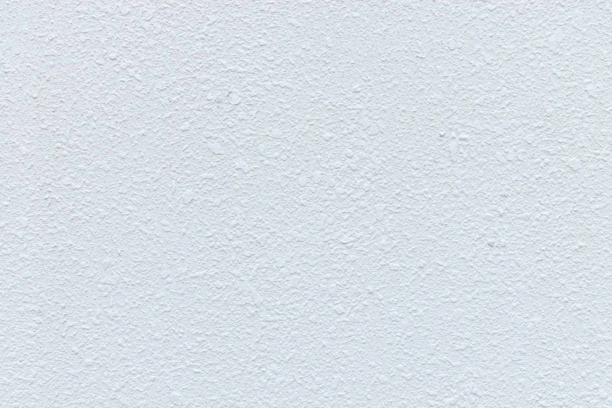 Orange-peel drywall texture in near darkness, waiting for the light pass