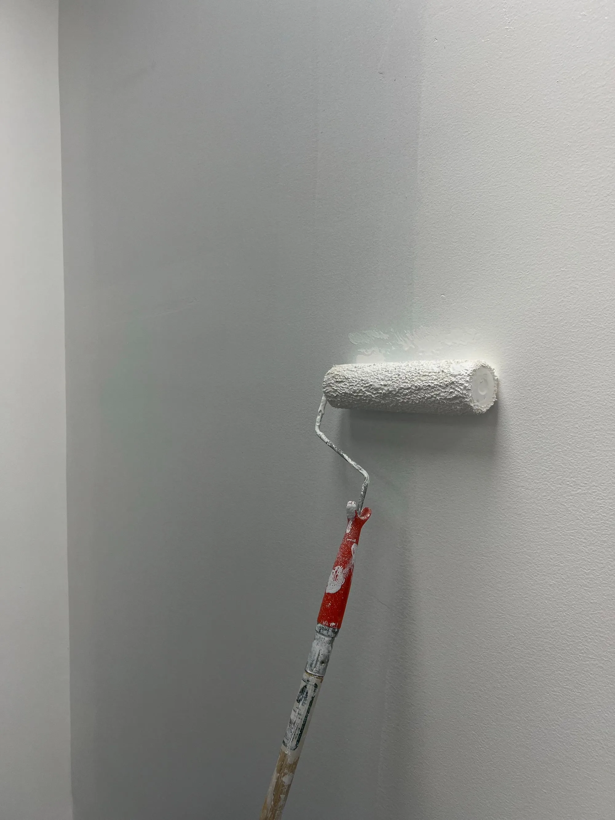 Roller putting fresh paint on a repaired wall